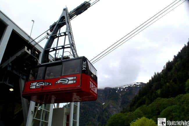 Scenic view of the Juneau Goldbelt Tramway on Mt. Roberts with a red tramcar and lush green mountains.