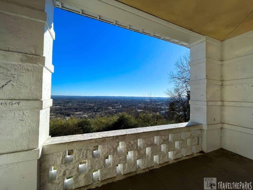 View from a white brick lookout over a landscape of trees and a distant town under a clear blue sky.