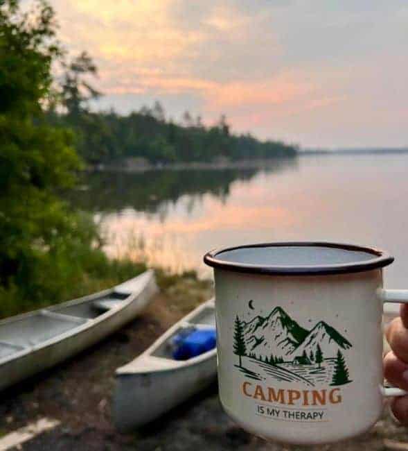 A campfire mug in front of the lake with canoes on the shoreline in Voyegeurs National Park