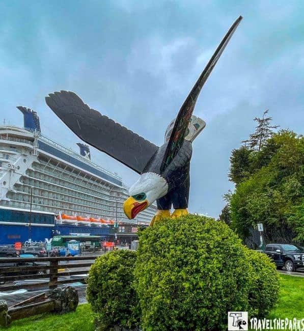 A statue of an eagle with a cruise ship in the background at Ketchikan Eagle Park Thundering Wings sculpture.