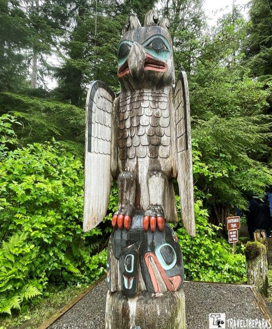 Totem pole with bird carving in the woods, Thunderbird and Whale design at Totem Bight.