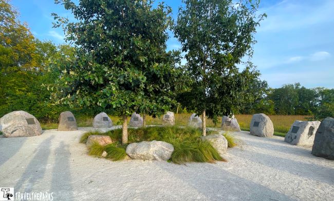 Prophetstown State Park outdoor area with two trees, large stones, and a circular arrangement of boulders with plaques.
