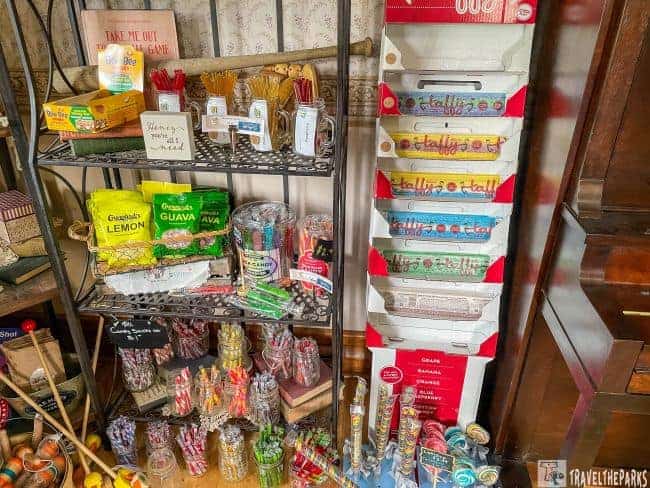 A candy and snack display in a shop with shelves and a taffy stand.