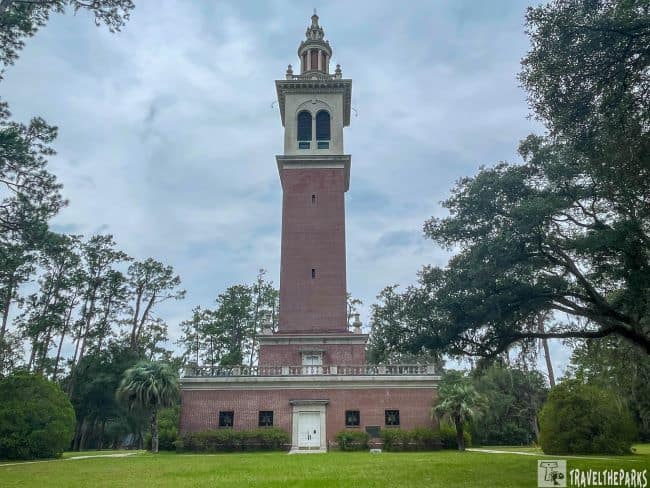 Tall brick tower at Stephen Foster Folk Culture Center, surrounded by trees and an overcast sky.
