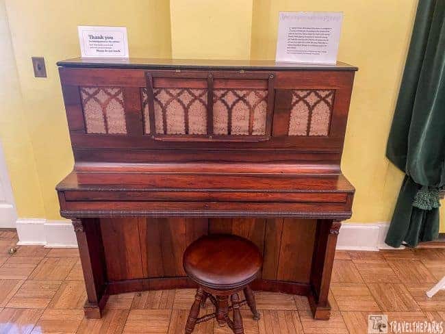 Stephen Foster Folk Culture Center State museum  antique wooden player piano with decorative panels and a wooden stool in front.