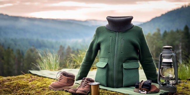 Fleece jacket and other camping items against a mountain background