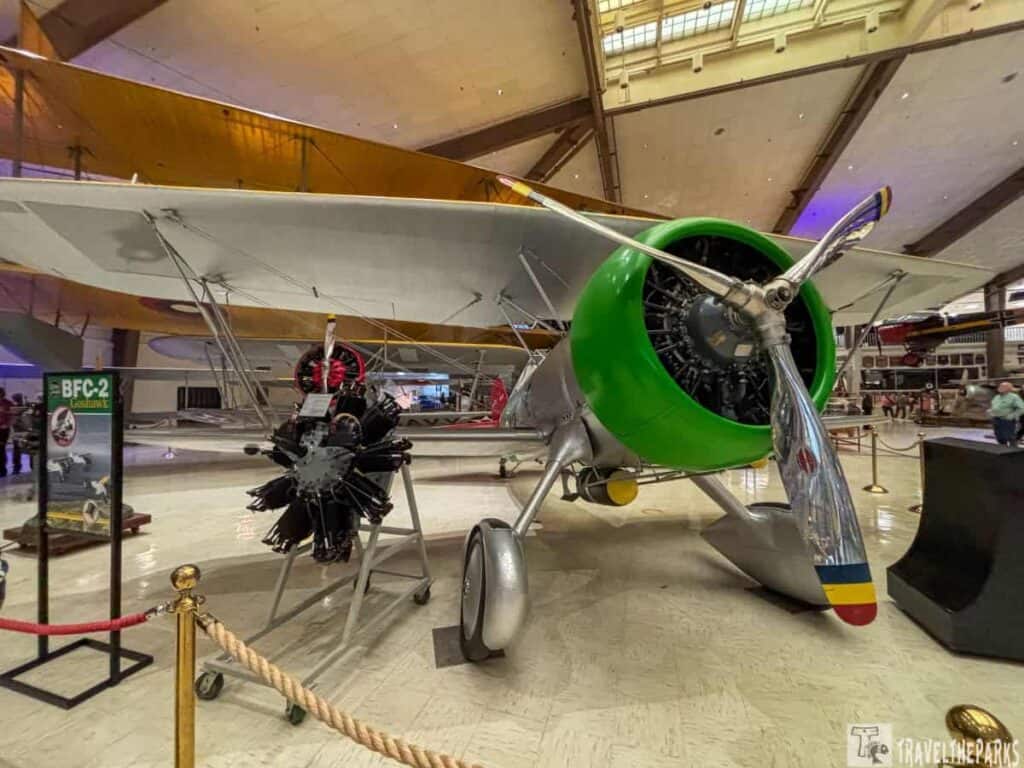 Curtiss BFC-2 Goshawk biplane in a museum exhibit with green engine cowling and silver propeller.