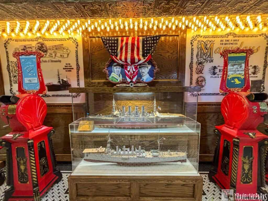 Pensacola Naval Aviation Museum exhibit with a naval ship model, American flag, and red vintage machines.