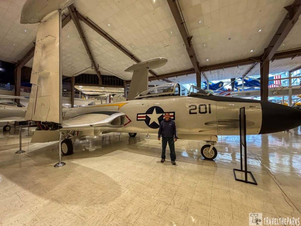 Man standing in front of The F-2D Banshee was a twin-engine, straight-wing aircraft primarily used by the U.S. Navy from the late 1940s through the 1950s. It was designed as a fighter-bomber, capable of performing strike missions and intercepting enemy aircraft.