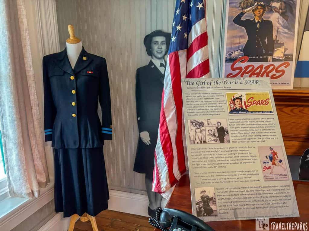 Display of a SPARS uniform, an American flag, and informational board at a museum.