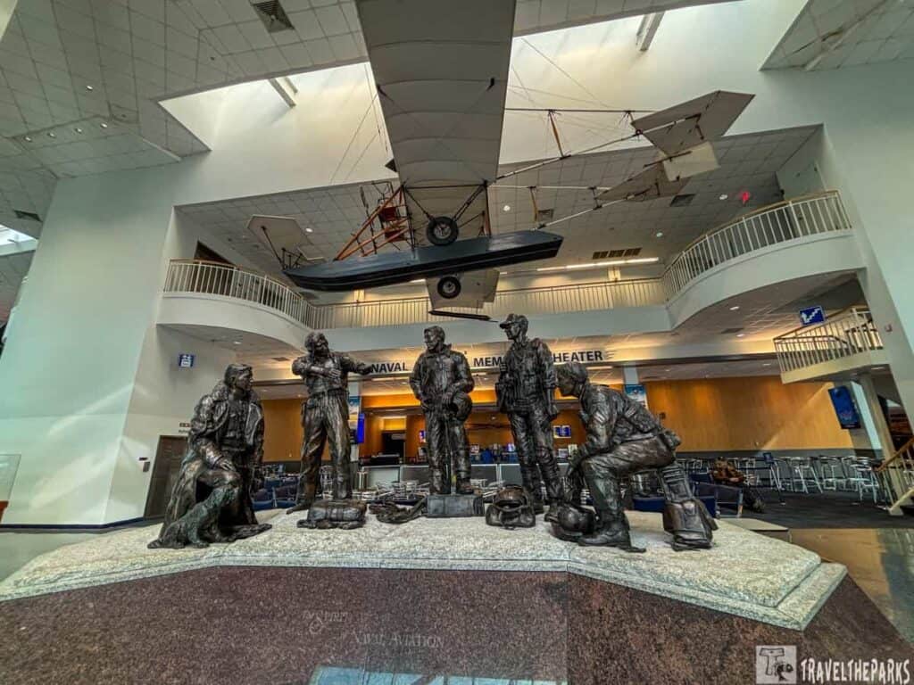 Pensacola Naval Aviation Museum bronze sculpture of naval aviators inside an atrium with a suspended  A-1 Triad model above.