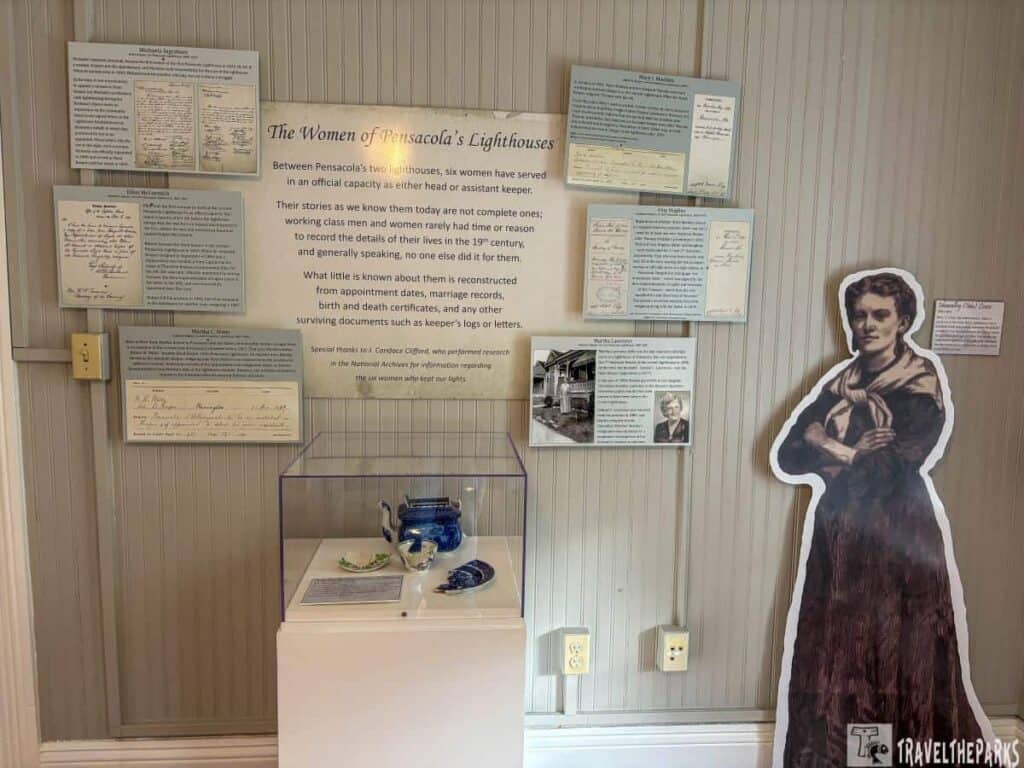 Exhibit on women lighthouse keepers in Pensacola featuring text panels, a cutout figure, and artifacts in a case.