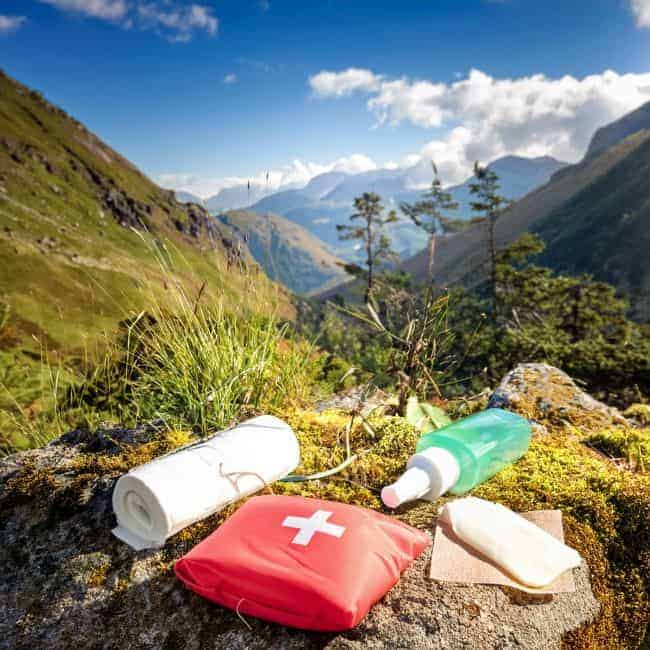 First aid items on a mossy rock in a mountainous landscape.
