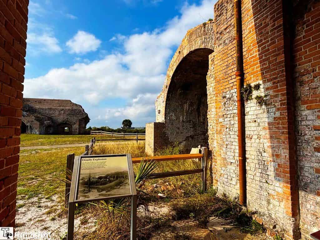 A historical brick ruin of Bastion D at Fort Pickens with an informational sign, under a partly cloudy sky.