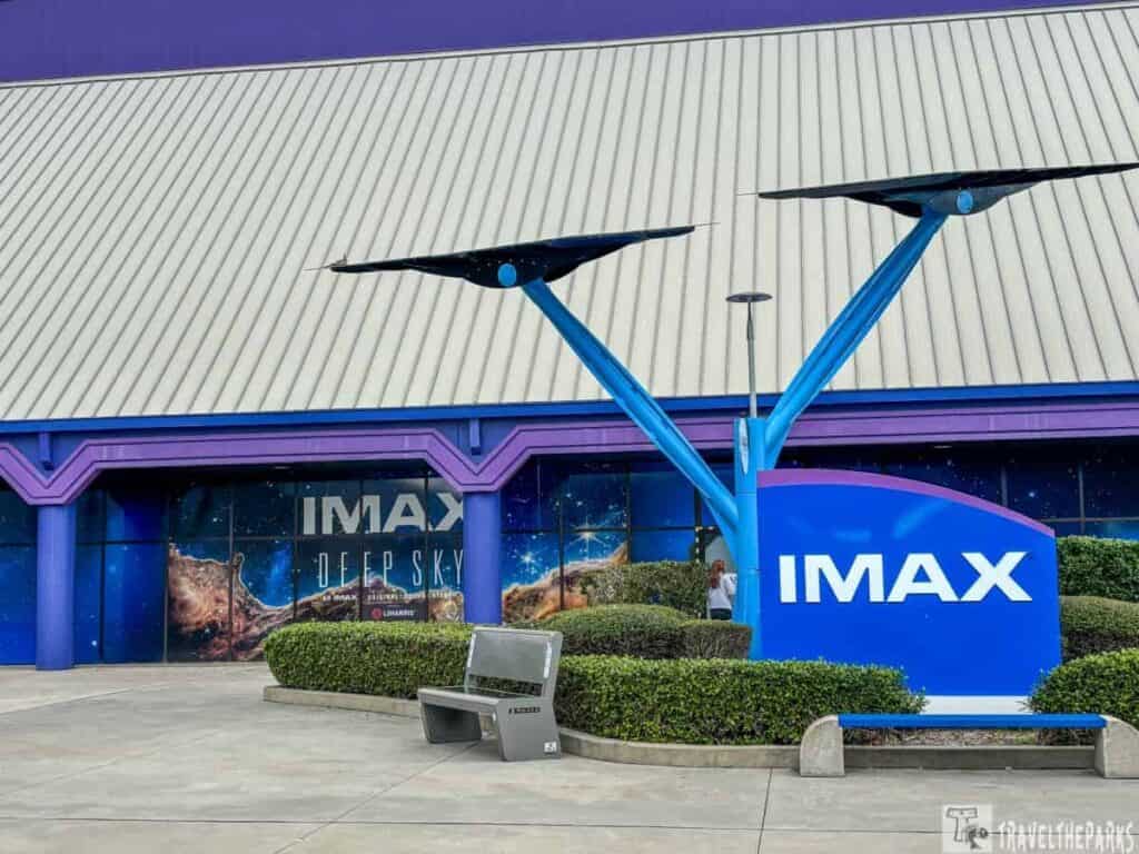 Entrance to an IMAX theater at Kennedy Space Center tour with a purple and blue sign and space-themed mural.