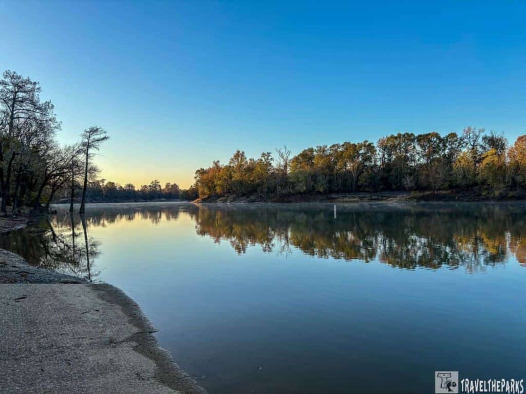 A calm Ouachita River at Moro Bay reflecting the early morning or late afternoon sky with trees along the shoreline.