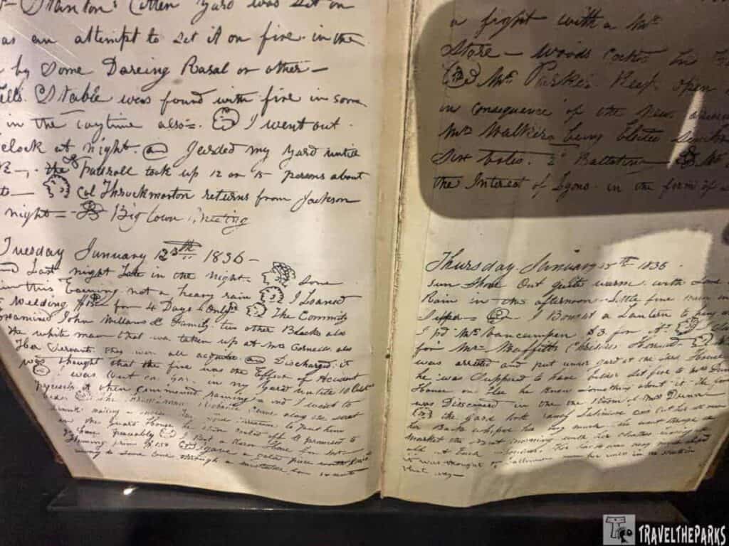 an open historical journal displayed under glass. The pages are filled with cursive handwriting in black ink, detailing events and observations. The left page is dated "Tuesday, January 8th, 1836," and the right page is dated "Thursday, January 9th, 1836." The handwriting is dense, covering most of the page, with some words underlined or emphasized with symbols.