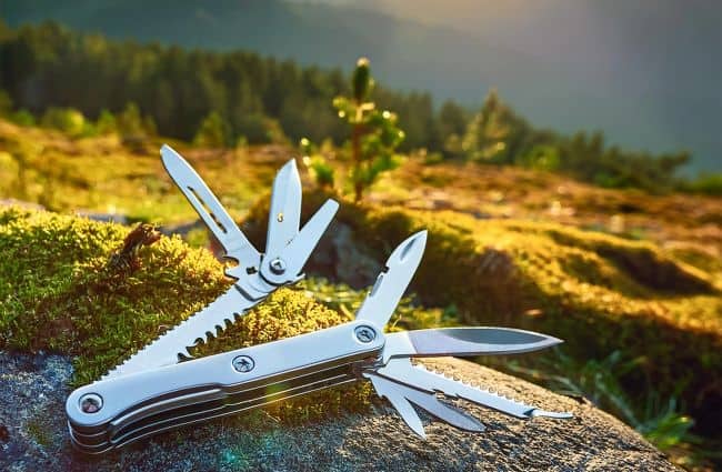 Multitool on a mossy rock with a forest background.
