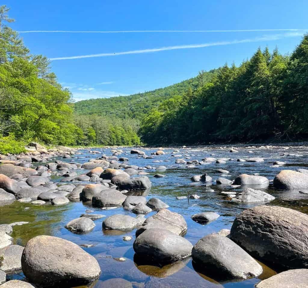 Boulder ridden creek in Georgia on a clear day with green luch mountains in the baclground.