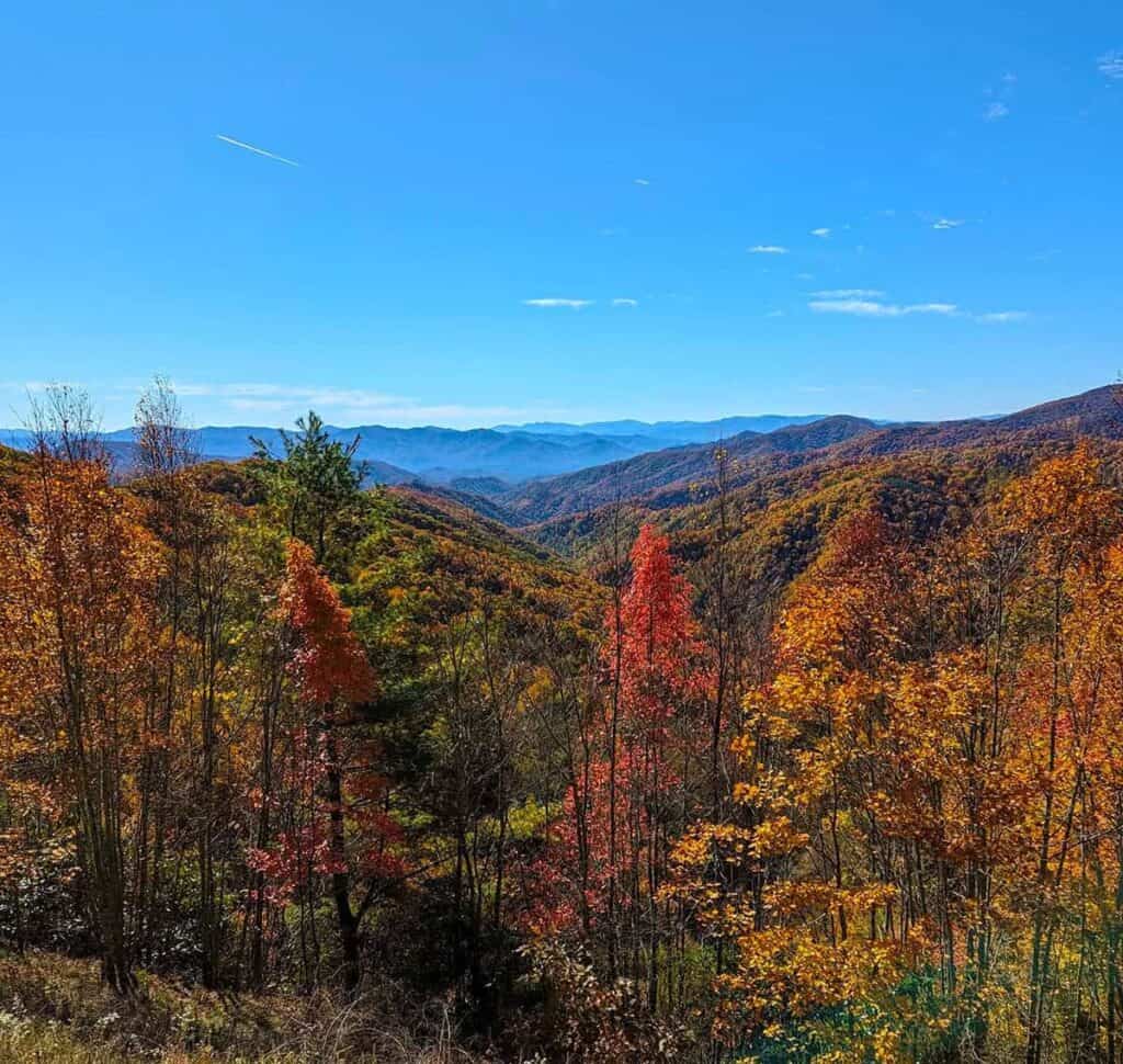 Autumn landscape with colorful fall foliage and rolling hills under a clear blue sky.