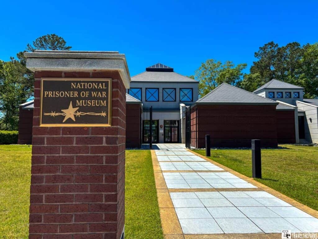 The Andersonville National Historic Site visitor center with pyramid-shaped roofs, a walkway, and surrounding trees.