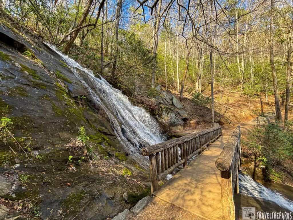 Wooden bridge beside a Juney Whank waterfall in a forest at Deep Creek in Smoky Mountains National Park.
