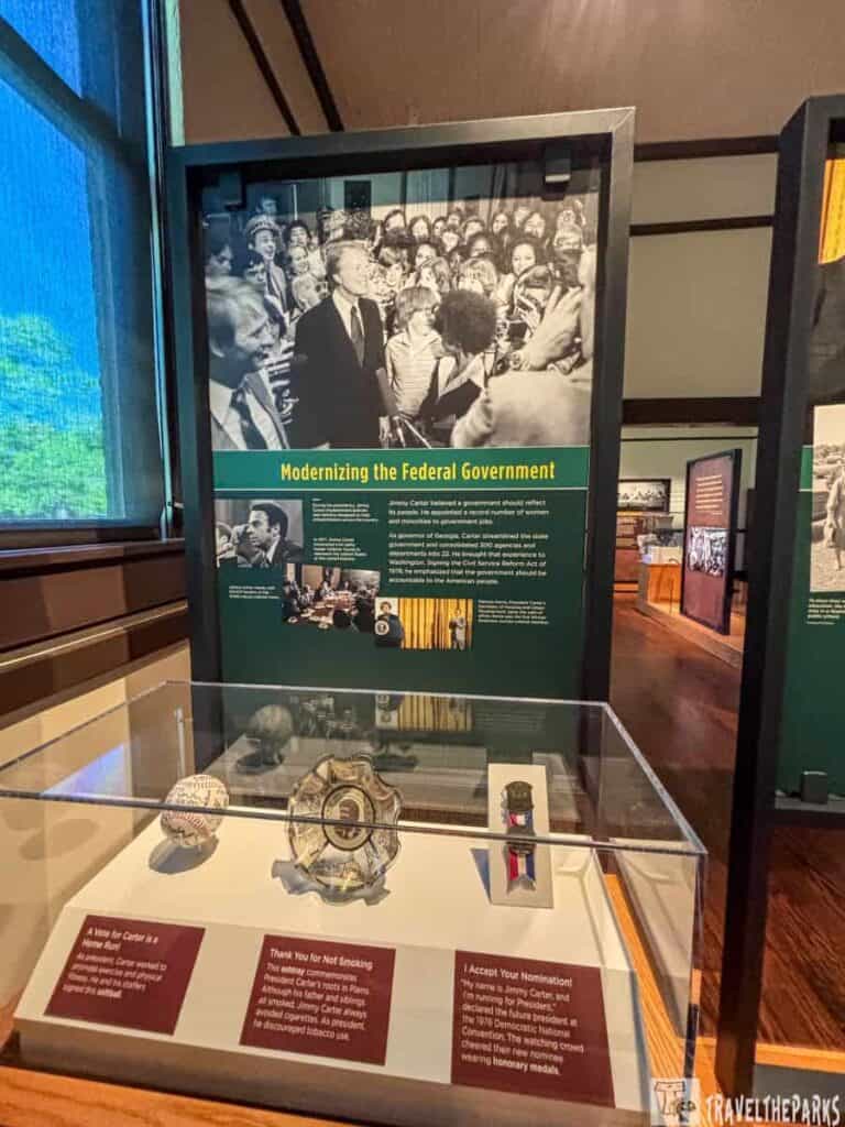 Museum exhibit featuring a panel and display case with historical artifacts related to modernizing the federal government.
