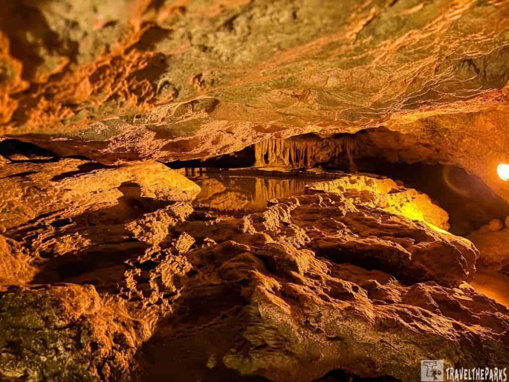 Interior of a Florida Caverns, with warm lighting, rocky formations, and a reflective pool.