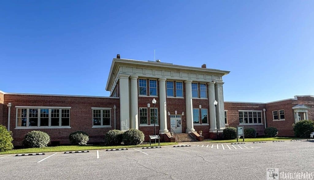 Historic Plains High School brick building with columns and symmetrical design under a blue sky. Visitor Center for Jimmy Carter National Historic Park.