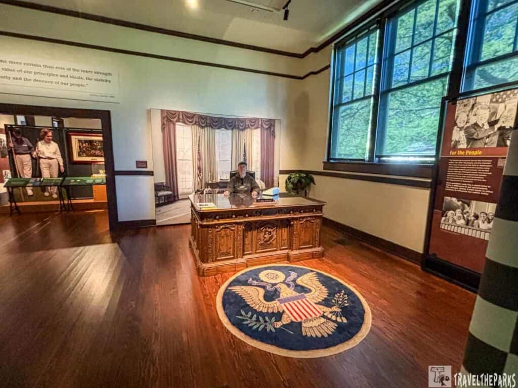 Room in Jimmy Carter National Historic Park with a desk, mannequin, and U.S. emblem rug.