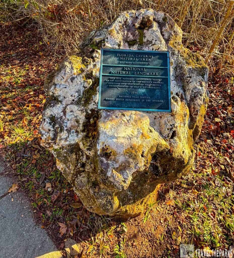 A large stone with a plaque set in a natural environment.