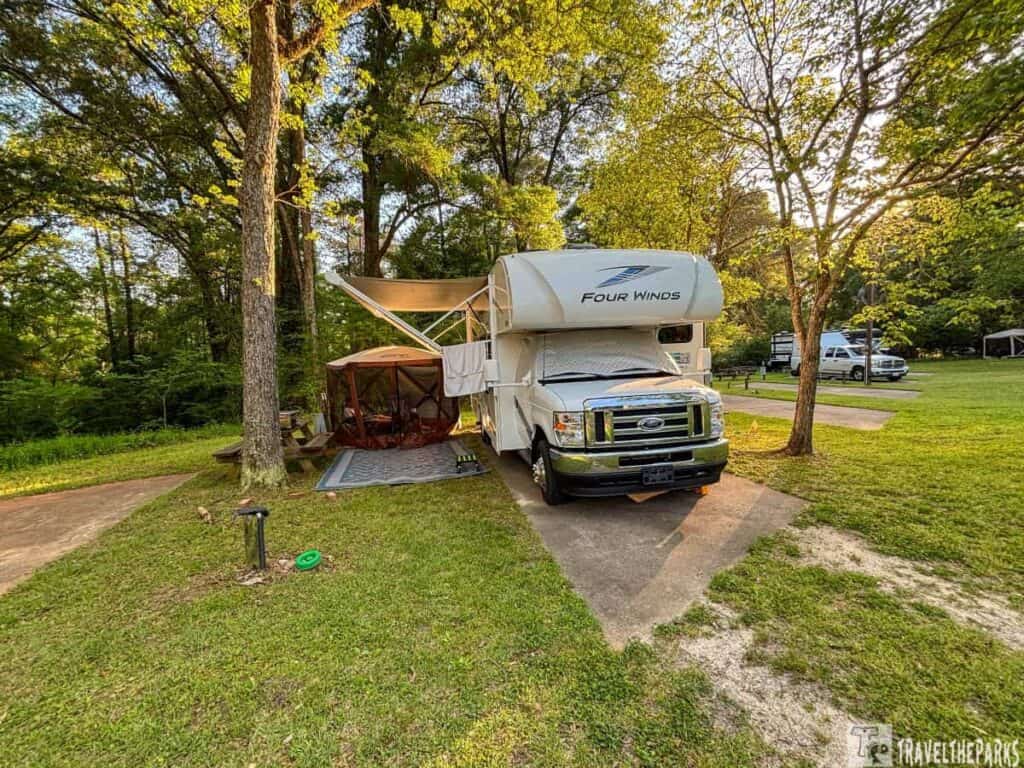 Motorhome with a canopy at a campsite in Andersonville Campground surrounded by trees.