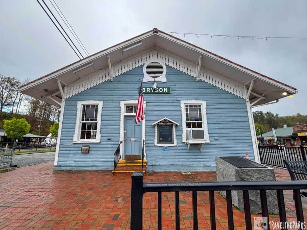 Blue wooden train Depot building labeled "BRYSON" with a triangular roof and American flag.