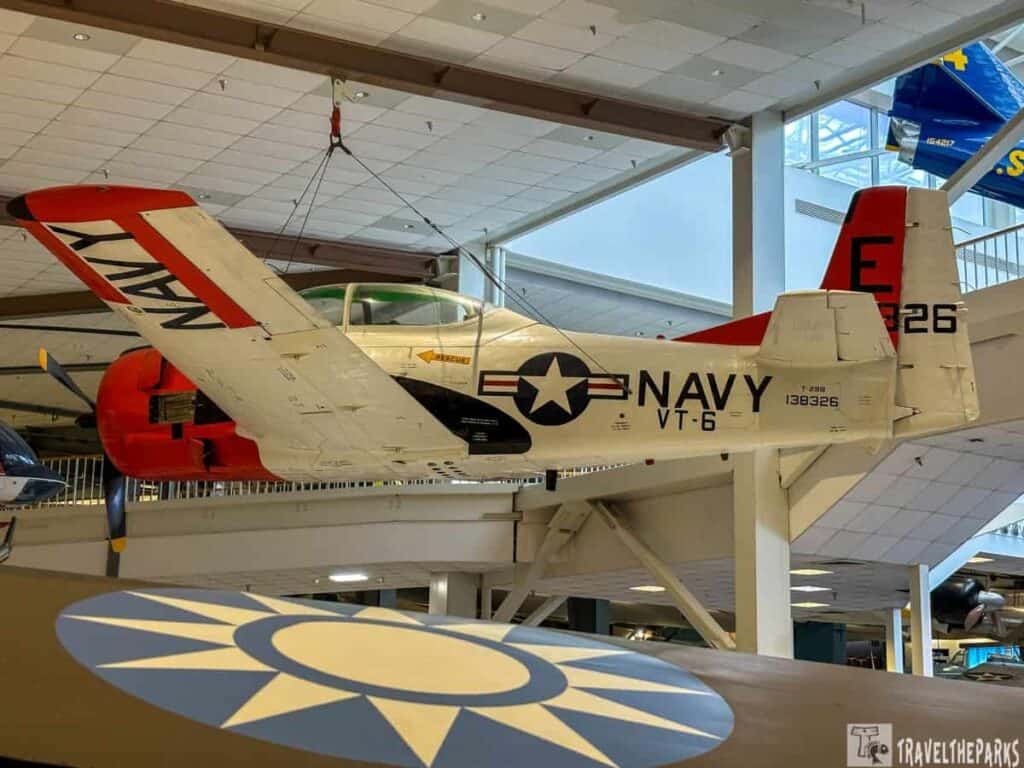 Vintage navy VT-6 Trainer aircraft suspended in an indoor display with red and white markings.