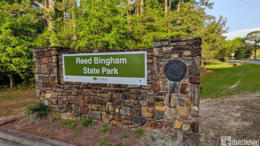 Entrance sign for Reed Bingham State Park on a stone wall with surrounding greenery.