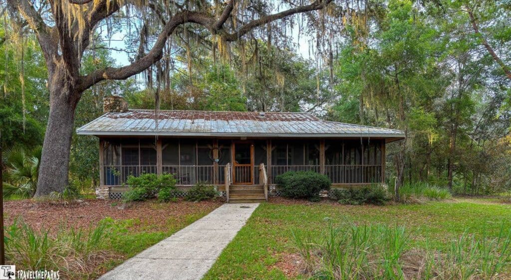 A rustic cabin with a metal roof and screened porch surrounded by trees at Silver Springs State Park.