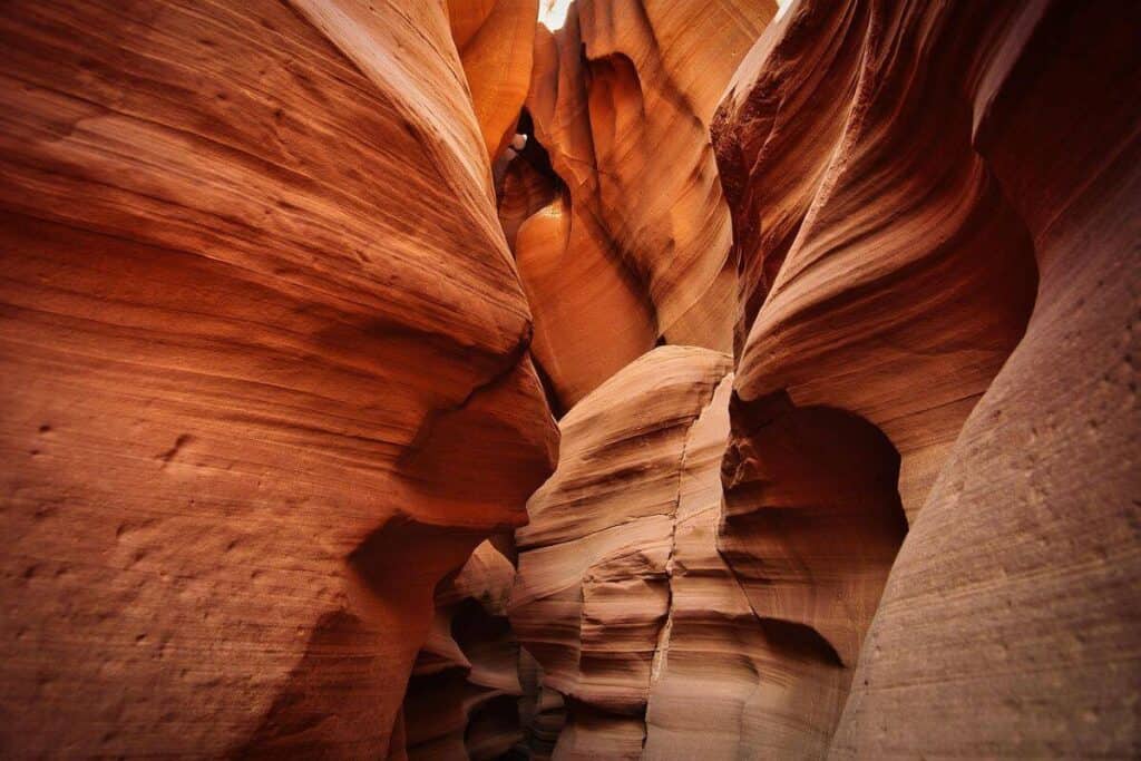 Narrow sandstone formations with warm orange and brown tones in Antelope Canyon, showing curving lines and textures.