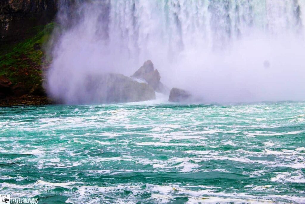Niagara Falls cascading into a turquoise river with rocky formations and mist.