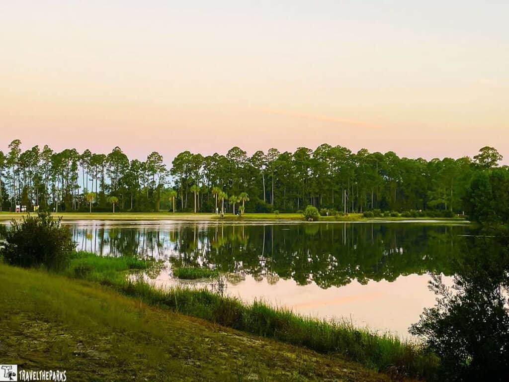 A tranquil lake at Blythe Regional Campground with trees reflected on the water under a pastel evening sky.