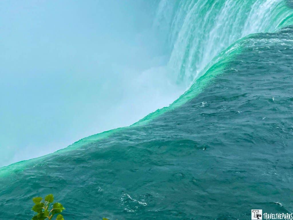 View of Niagara Falls with emerald green water cascading over the edge, creating mist.