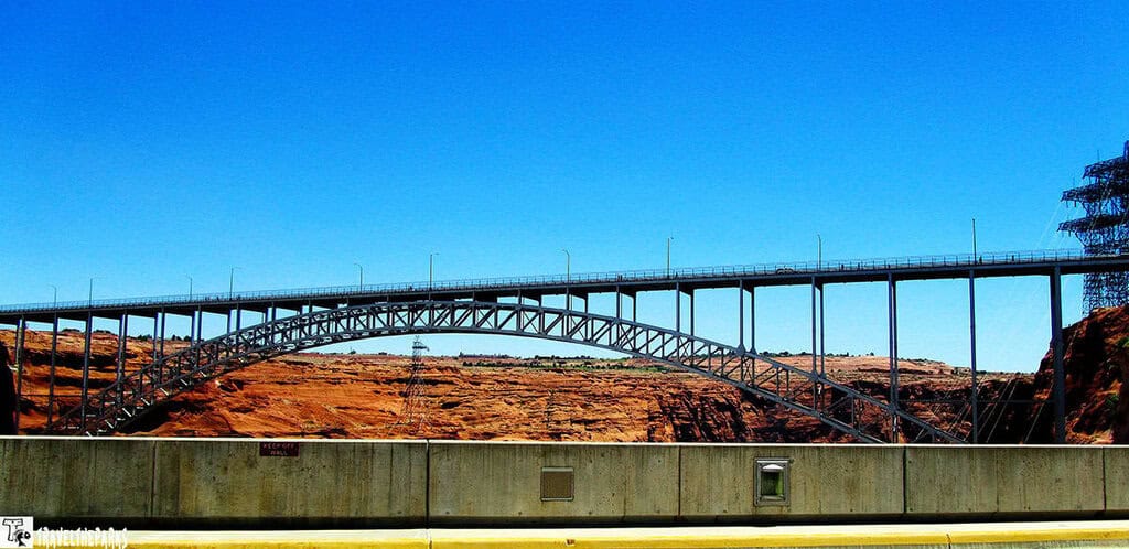 Steel arch bridge over colarado River at the Glen Canyon dam with a blue sky.