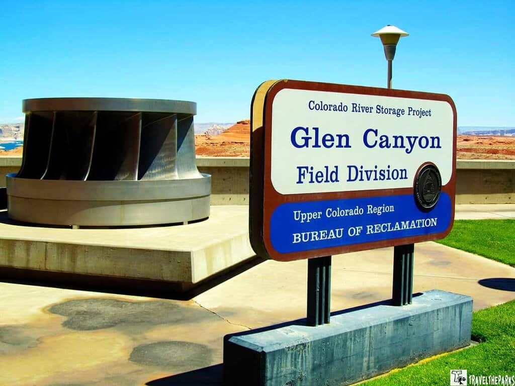 "Sign for Glen Canyon Field Division with a turbine and desert landscape in the background."