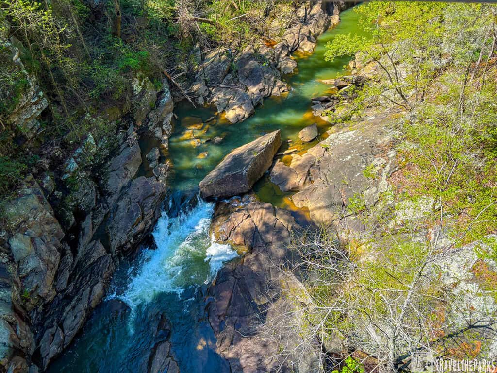 Aerial view of Tallulah Gorge with a river flowing between rocky cliffs and surrounded by greenery.