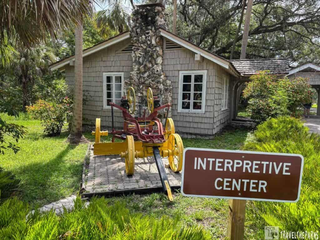 A rustic building and old fire engine at Hillsborough River State Park's Interpretive Center, with a surrounding lush garden.