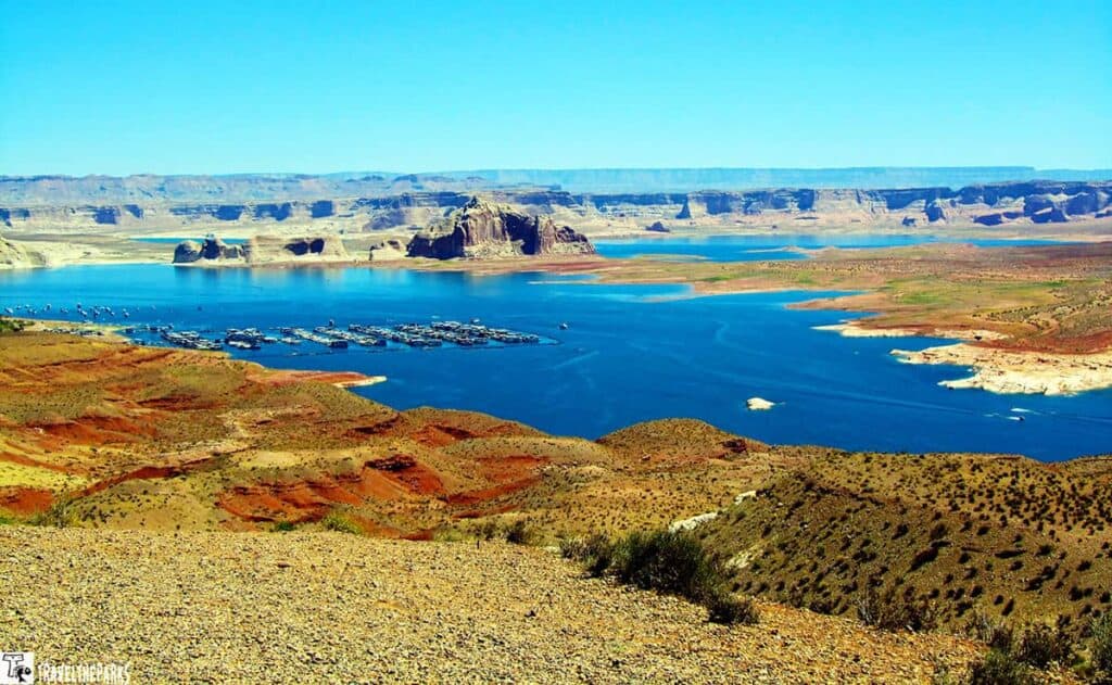 View of Wahweap Marina with boats on Lake Powell, surrounded by red and tan cliffs.
