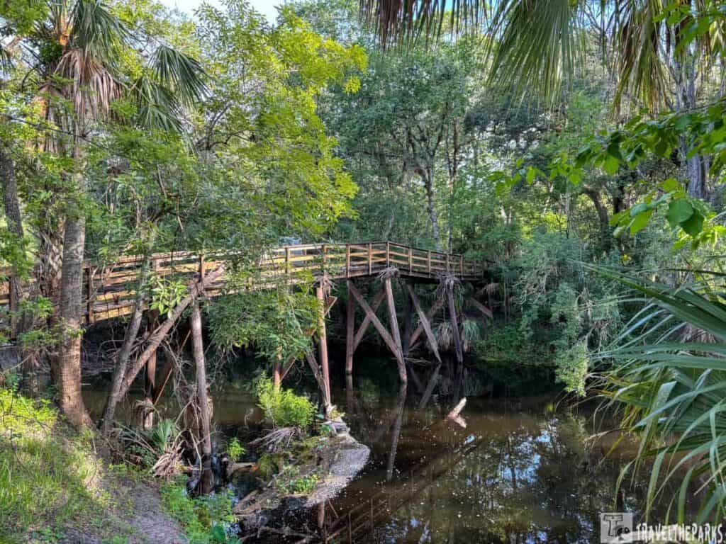 Wooden footbridge over a river surrounded by dense greenery at Hillsborough River State Park.