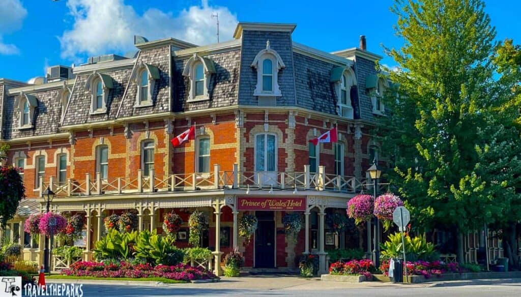 Historic Prince of Wales hotel with dormer windows, Canadian flags, and colorful hanging plants.