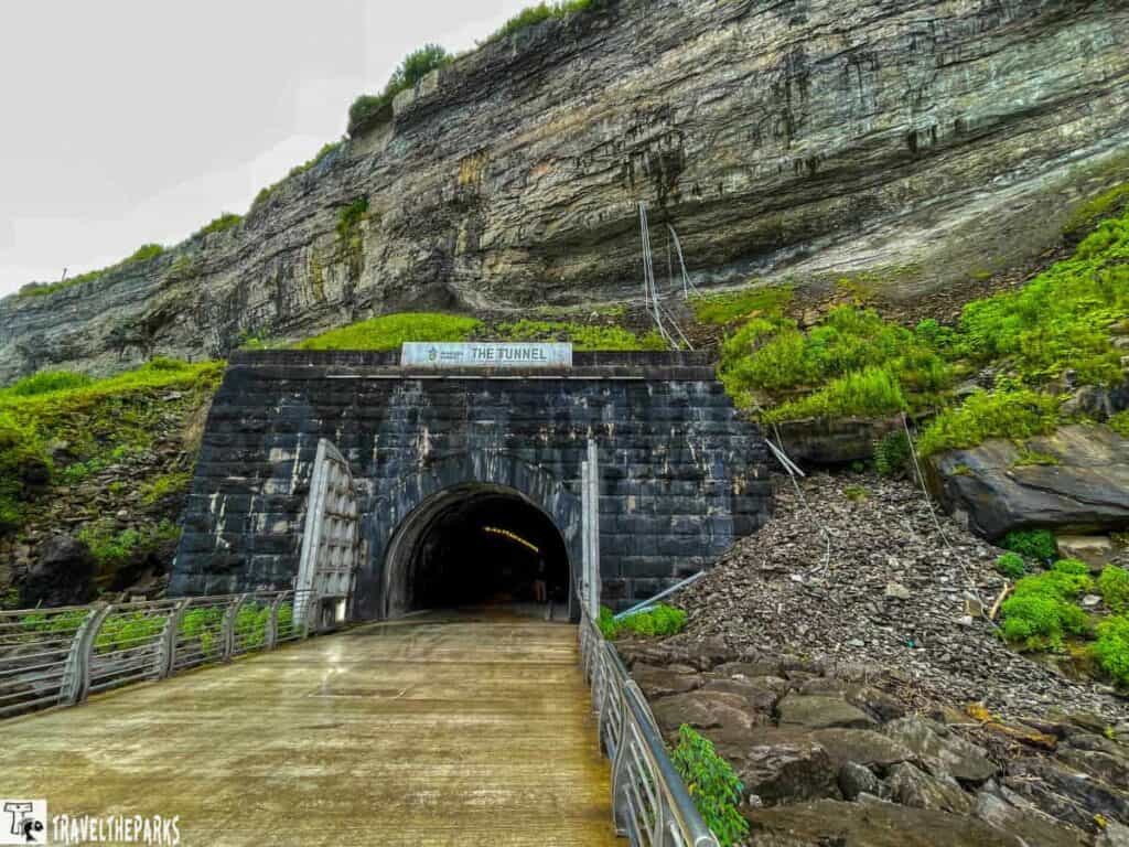 Entrance to a tunnel within a rocky cliff face, with a pathway leading up to it.