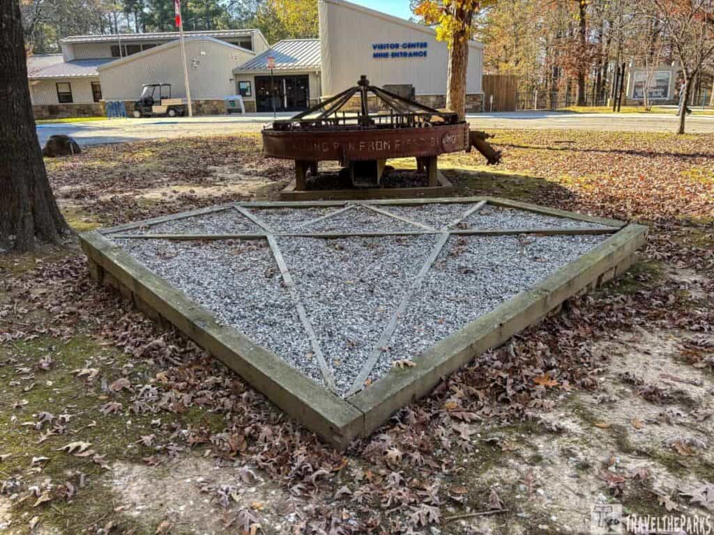 Diamond-shaped gravel plot with metal framework and a visitor center in the background.