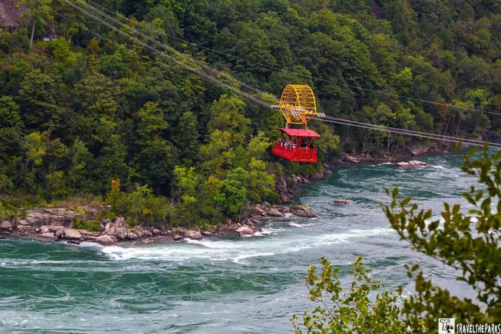 Whirlpool Aero Car above the Niagara River with a forested backdrop.